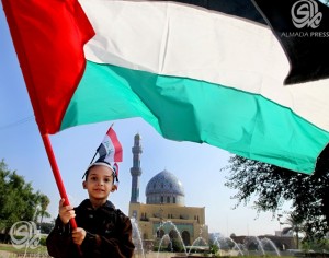 طفل عراقي يحمل علم فلسطين تعبيرا عن التضامن 